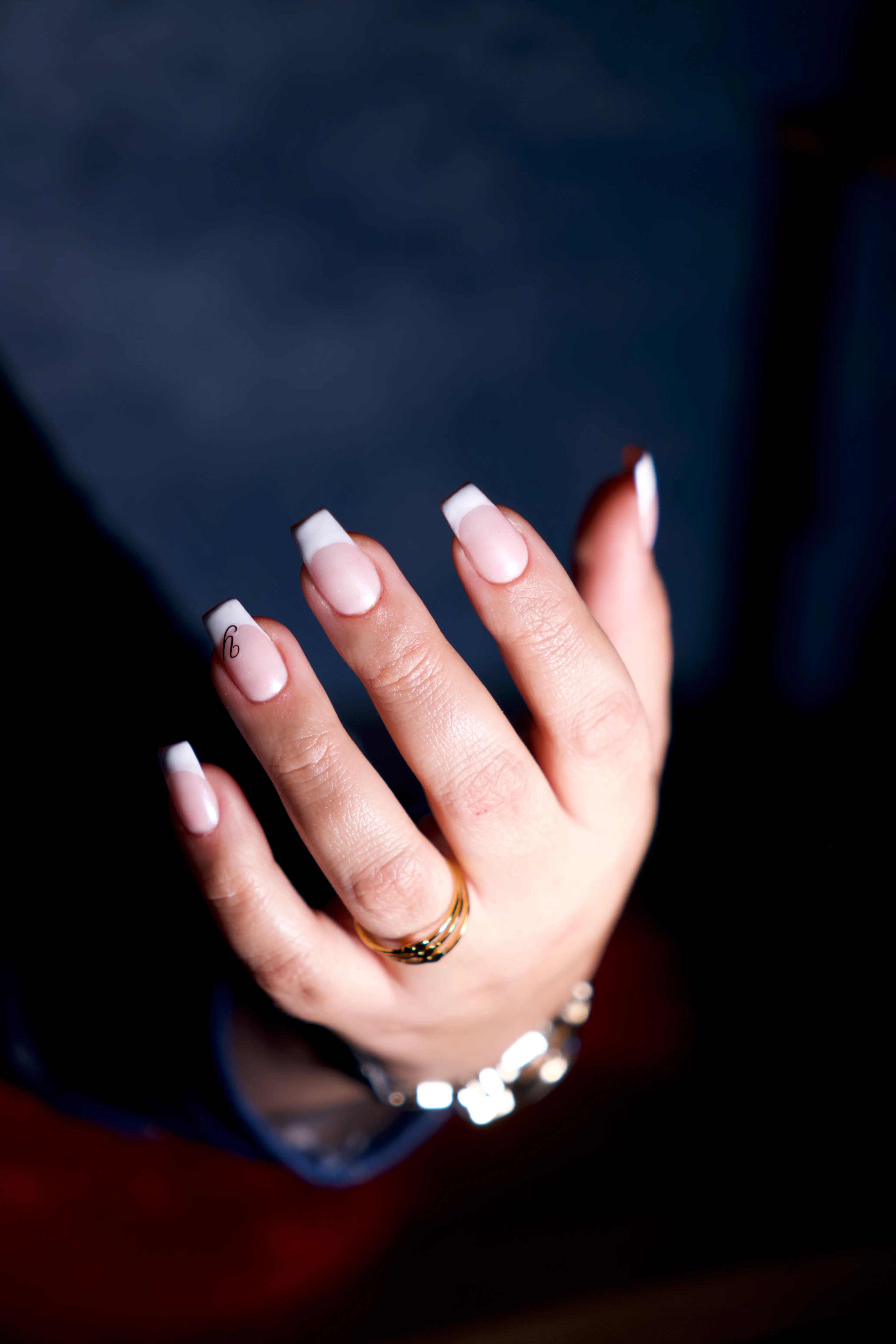 An elegant french-tip manicure on a hand wearing fine jewellery