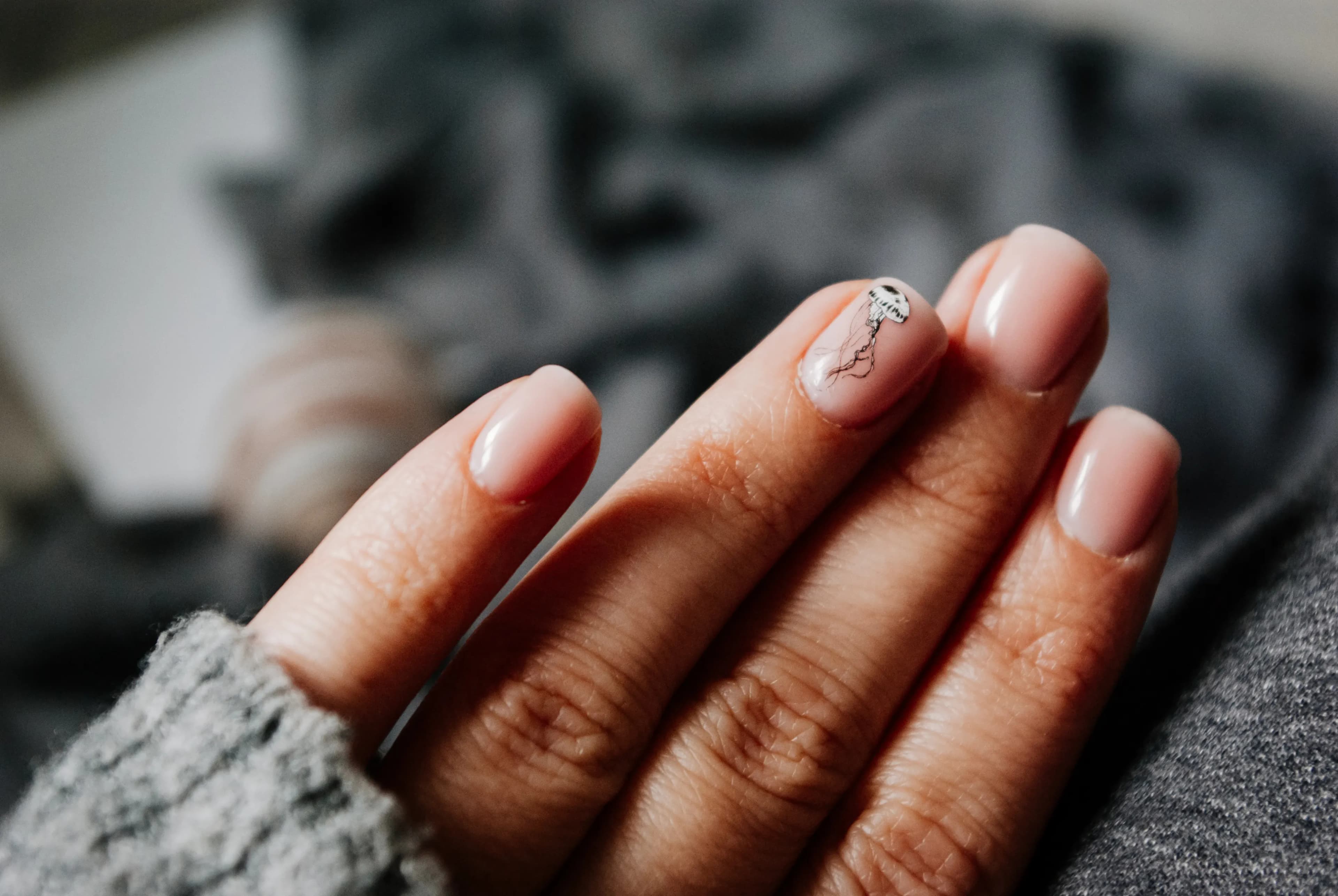 Pastel nail art displayed against a charcoal-grey knitted fabric